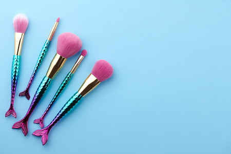 Fish shape glossy make up brushes close up on blue backgroundの写真素材