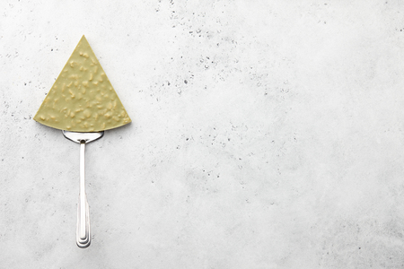 Pizza slice or triangle shaped chocolate piece on metal spatula on stone backgroundの写真素材