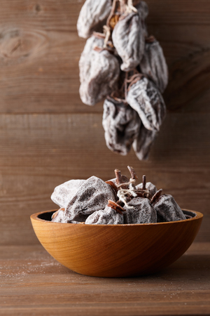 Dried persimmon in wooden bowl on planks background, close up viewの写真素材