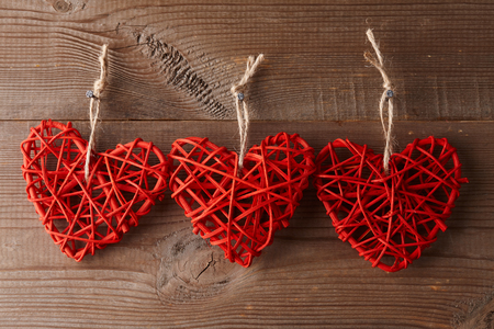 Handmade red rattan hearts hanging on old fence. Valentine's day decorationの写真素材
