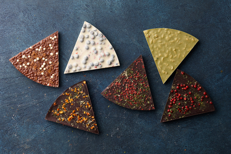 Triangle shape chocolate pizza slices with diverse kinds of toppings on blue background, top viewの写真素材