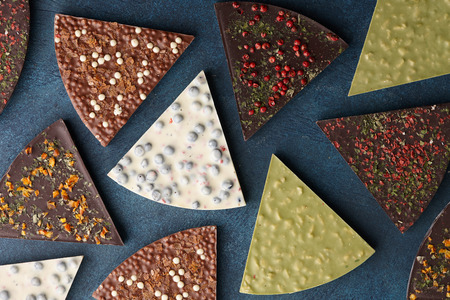 Triangle shape chocolate pizza slices with diverse kinds of toppings on blue background, top viewの写真素材
