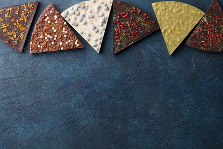 Triangle shape chocolate pizza slices with diverse kinds of toppings on blue background, top viewの写真素材