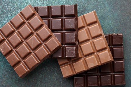 Various milk and dark square shape chocolate bars on wooden background, top viewの写真素材