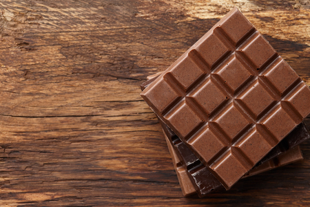 Various square shape chocolate bars pile on brown wooden background, top viewの写真素材
