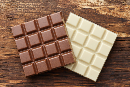 Milk and white square shape chocolate bars on textured brown wooden background, top viewの写真素材
