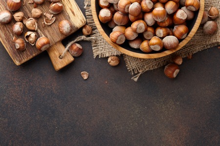 Hazelnuts in a wooden bowl on brown textured background, copy spaceの写真素材