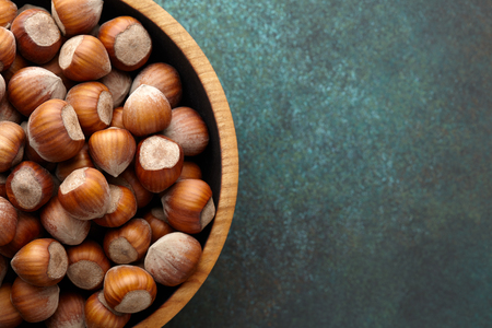 Hazelnuts in a wooden bowl on blue green textured background, copy spaceの写真素材