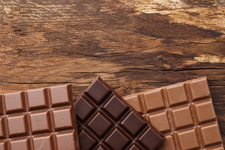 Various square shape chocolate bars on brown wooden background, top viewの写真素材