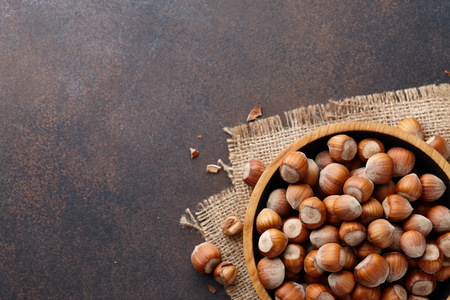 Hazelnuts in a wooden bowl on brown textured background, copy spaceの写真素材