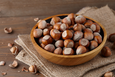 Hazelnuts in a wooden bowl on wooden planksの写真素材