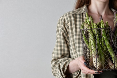 Woman in plaid shirt holding fresh seasonal asparagus in hands. Gardening, farming and natural food concept.の写真素材