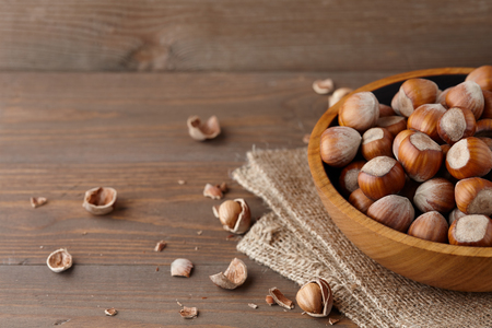 Hazelnuts in a wooden bowl on wooden planks, copy spaceの写真素材