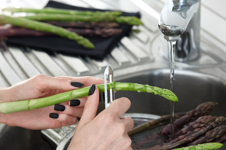Green and purple asparagus peeling in the kitchen, close up viewの写真素材