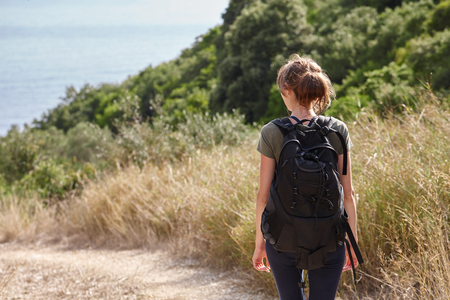 Woman with a backpack getting down to wild beach in Corfu, Greece. Mountains hiking.の写真素材