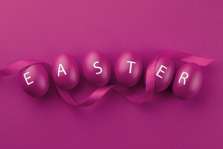 Purple Easter eggs with letters arranged in a word Easter on purple background. Holiday concept.の写真素材