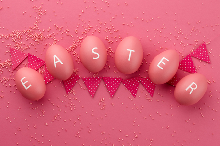 Pink Easter eggs with letters arranged in a word Easter on pink background. Holiday concept.の写真素材
