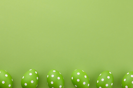 Green dotted Easter eggs on green background, copy spaceの写真素材