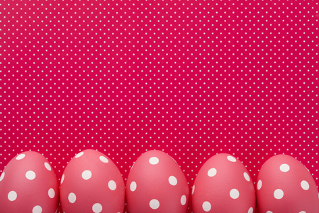 Pink dotted Easter eggs on crimson dotted background, copy space. Holiday concept.の写真素材
