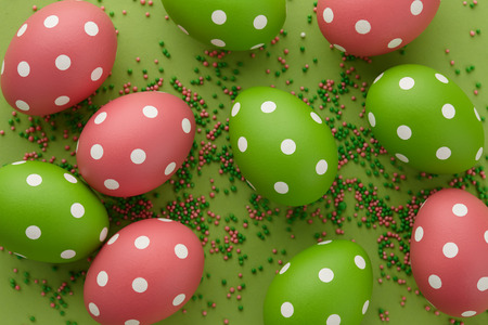 Green and pink dotted Easter eggs on green background, top view. Holiday concept.の写真素材