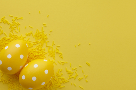 Pair of yellow dotted Easter eggs on yellow background, top view. Holiday concept.の写真素材