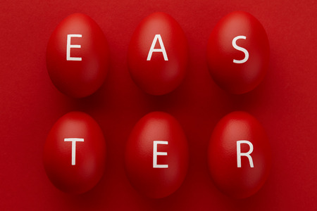 Red Easter eggs with letters arranged in a word Easter on red background. Holiday concept.の写真素材