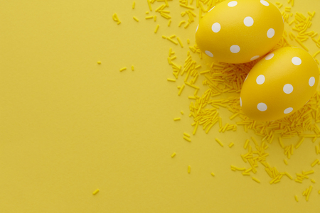 Pair of yellow dotted Easter eggs on yellow background, top view. Holiday concept.の写真素材