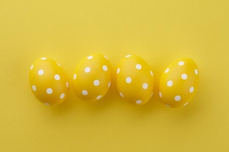 Yellow dotted Easter eggs on yellow background, top view. Holiday concept.の写真素材