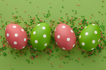 Green and pink dotted Easter eggs on green background, top view. Holiday concept.の写真素材
