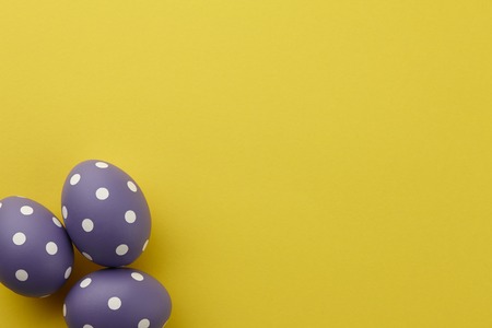Purple dotted Easter eggs on yellow background, top view. Holiday concept.の写真素材