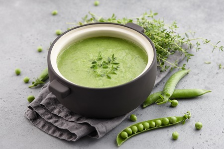 Fresh green pea soup served in bowl with thyme on gray concrete background, copy spaceの写真素材