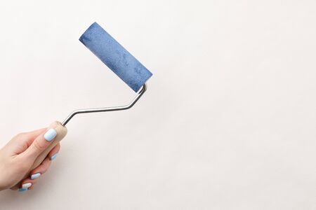 Female hand painting wall with roller in blue color, copy spaceの写真素材