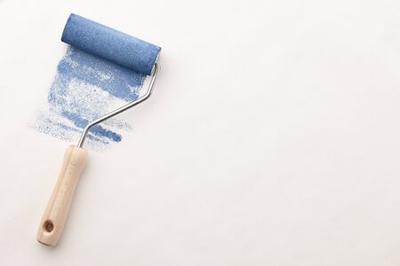 Sponge roller with blue paint on white wallpaper background, copy spaceの写真素材