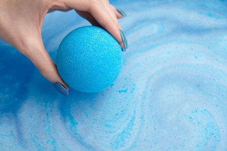 Woman's hand putting blue bath bomb into water, copy spaceの写真素材