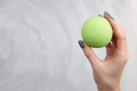 Woman's hand putting green bath bomb into water, copy spaceの写真素材