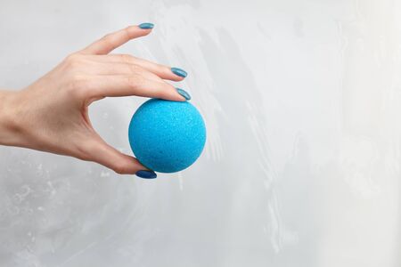 Woman's hand putting blue bath bomb into water, copy spaceの写真素材