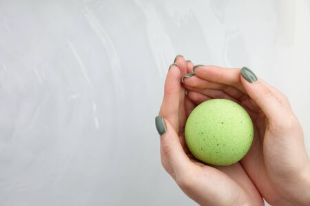 Woman's hand putting green bath bomb into water, copy spaceの写真素材