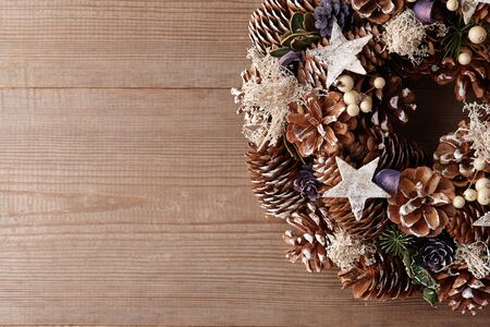 Christmas wreath decorated with pine and fir tree cones on wooden door, close up viewの写真素材