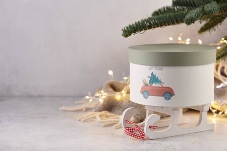Gift box with holiday car print under Christmas tree on wool blanket and lights background, copy spaceの写真素材