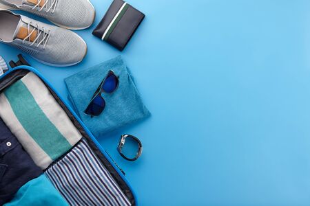 Packing blue travel suitcase on blue background, top viewの写真素材