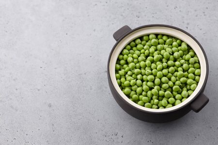 Fresh green peas in ceramic pot on concrete background, close up viewの写真素材