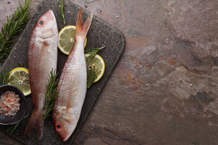 Fresh red mullet fish cooking on stone background, top viewの写真素材