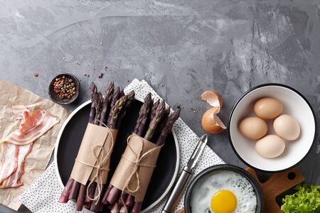Gourmet breakfast with fresh purple asparagus, fried eggs and bacon, top viewの写真素材