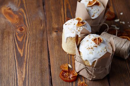 Easter cakes with candied fruits and almond crumbs wrapped in kraft paper on brown wooden tableの写真素材