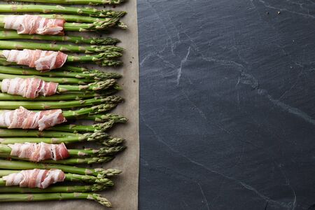 Raw green asparagus wrapped with bacon ready for baking, top viewの写真素材