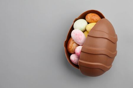 Chocolate Easter egg with colorful candies inside, copy spaceの写真素材
