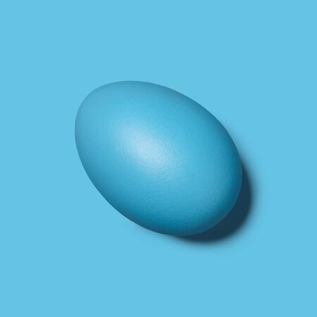 Blue painted Easter egg on blue background, close up viewの写真素材