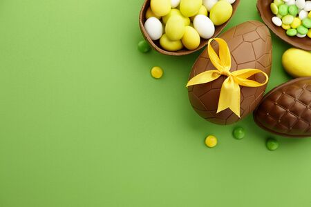 Chocolate Easter eggs and colorful candies on green background, copy spaceの写真素材