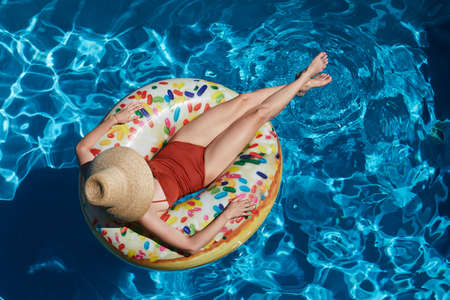 Young woman on inflatable donut ring in swimming pool, summer vacation conceptの写真素材