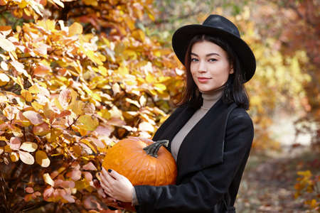 Woman in black with Halloween pumpkin in autumn forest, witch characterの写真素材